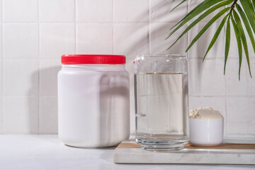 Collagen protein powder with glass of water on white kitchen table