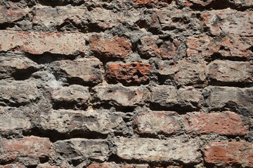 A detailed close-up of an old red brick wall in Siena, Italy
