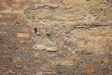 Red bricks visible beneath the peeling plaster of a wall