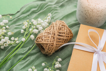 Rustic twine ball and gift box with flowers on green fabric background