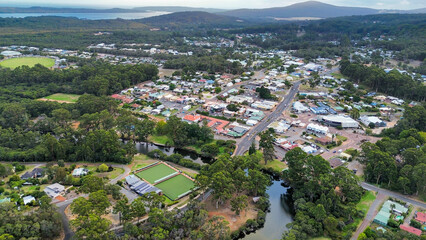 Aerial image of Small rural town, Denmark Western Australia captured from above showing the river, bowling green, main roads, buildings. The background has beautiful landscape with hills and water 
