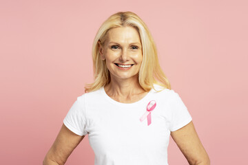 Smiling woman wearing pink ribbon supporting breast cancer awareness