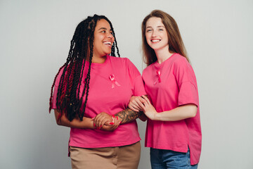 Two smiling women supporting breast cancer awareness holding hands