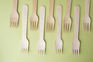 Wooden disposable forks  on pastel green background