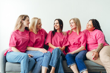 Smiling women wearing pink ribbons are showing support for breast cancer awareness