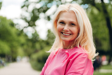 Smiling woman wearing pink ribbon supporting breast cancer awareness in park