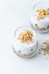 Yogurt parfait with granola and blueberries in glass cups