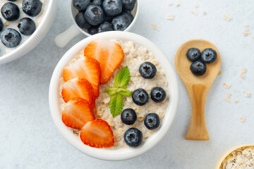 Oatmeal with strawberries and blueberries on white background