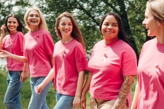 Women wearing pink ribbons supporting breast cancer awareness walking in park