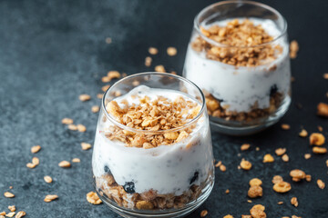 Parfaits with granola and yogurt in glass on dark  background