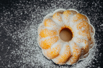 Bundt cake with powdered sugar on black background