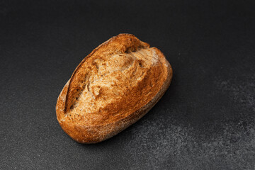 Rustic whole grain bread resting on a dark surface