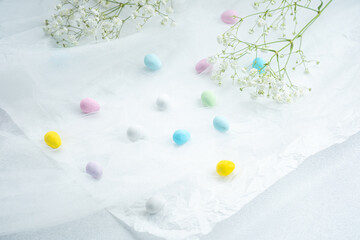 Colorful candies scattered on delicate white tissue with flowers