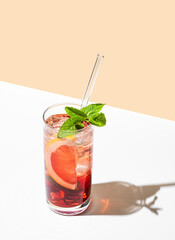 Refreshing cocktail with grapefruit, mint and ice in a glass on a white yellow background with shadow.