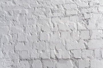 Textured white brick wall with uneven surface in bright light