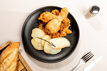 Top view of baked chicken with vegetable sauce and sliced potatoes.