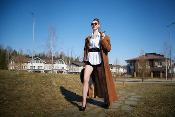 Fototapeta premium Confident woman in stylish outfit poses outdoors against modern homes in bright daylight