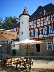 Sanierte alte Häuser in Naturfarben mit Fachewerk und Sonnenschirm vor blauem Himmel im...