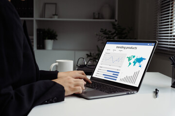 Close up of hands using laptop showing trending product dashboard with charts and maps