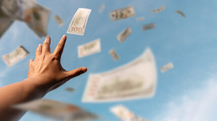 Hands reaching for money floating in the air suggest the endless pursuit of wealth, ambition, and financial opportunity in a globalized world