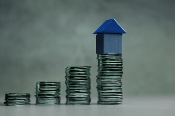 a Blue house model on Stacked coins representing mortgage, Loan, Real estate investment and Saving Goal for a Dream House