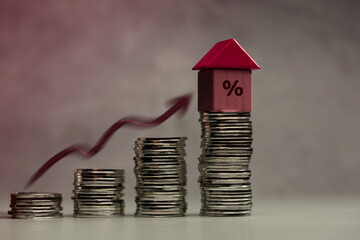 Stacked coins with house and percentage symbol representing mortgage interest rates and real estate investment