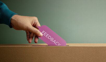 Hand putting feedback card in box symbolizing customer review, survey response, and constructive...