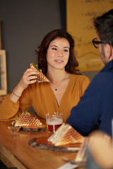 Young woman eat a club sandwich in a bar