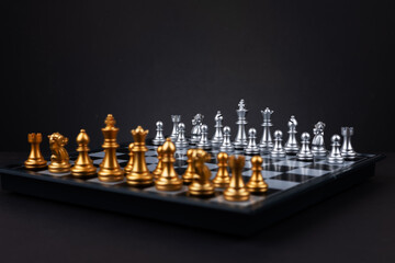 Gold and silver chess figures placed on wooden chessboard. Intellectual duel and tactical battle in...