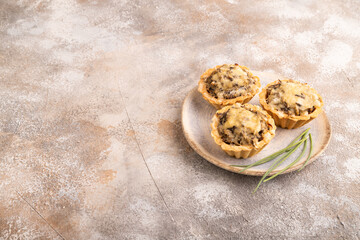 Tartlets with meat and cheese on brown concrete. side view, copy space