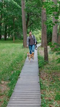 young man in plaid shirt playing training petting hugging and kissing his dog during summer park walk happy loving companionship concept lifestyle	