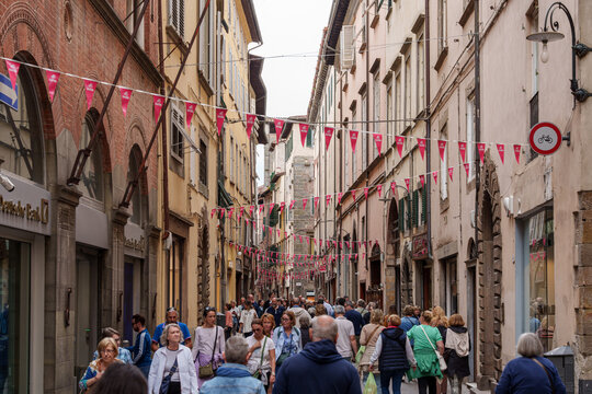 Fototapeta Busy narrow street in Lucca, Italy, with old buildings and walking tourists.