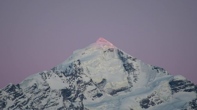 Snow covered Tetnuldi peak in Caucasus mountains, Svaneti region, Georgia during winter sunset under purple sky conditions