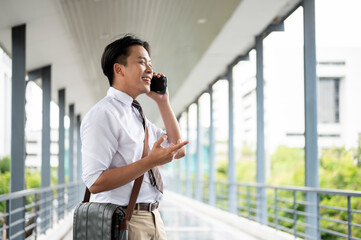 Smiling businessman or office worker holding phone talking while walking on a pedestrian footbridge.