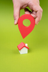 New place of residence. Hand with geolocation button points to the house. Depicts home search, real estate apps, or relocation decisions. Property selection, moving, or housing preferences