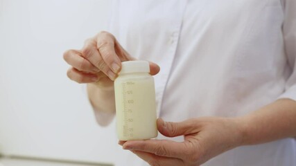 An individual holds a bottle of donor breast milk, showcasing the resource in a medical setting.