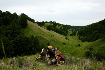 Female traveler hugs his two dogs against backdrop of the Zagajicka brda hills in Serbia. A moment...