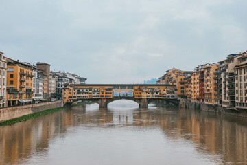 ponte vecchio florence italy with water reflections and cloudy sky