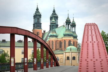 Red bridge leading to the Cathedral of St. Peter and Paul in Poznan, Poland, with green domes...