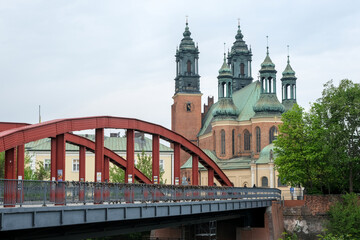 Red bridge leading to the Cathedral of St. Peter and Paul in Poznan, Poland, with green domes...