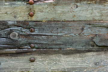 The close-up view reveals the intricate surface of aged wooden planks with rusted nails, highlighting natural wear and rustic charm.