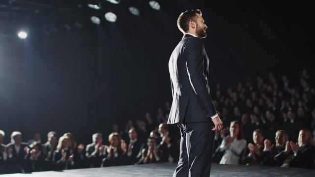 Professional speaker addresses audience at an elegant event in a well-lit theater, showcasing confidence and style