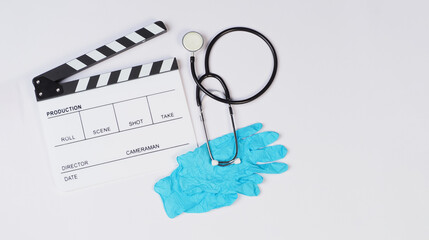 Clapperboard with stethoscope and latex glove on white background.