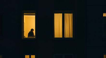 Person sitting alone in a dimly lit room at night