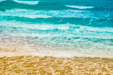 Sea waves rolling on a sandy beach. Close-up of the ocean near the coast. Background on the theme of tourism and family vacation by the water.