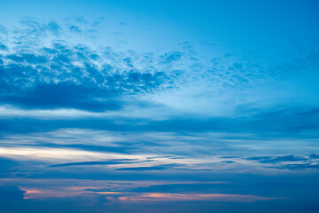 Blue sky with a pink stripe at the horizon. Calm background with evening clouds.