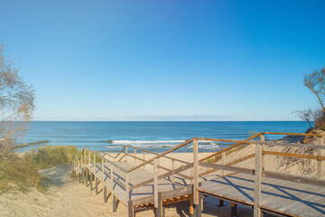 Wooden stairs leading through coastal thickets to the beach. Empty background on the theme of recreation and hiking.