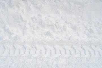 Close-up of tractor tracks on snow-covered cobblestones. Tire tracks on a winter road.