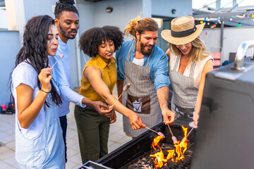 Friends grilling sausages at rooftop barbecue party
