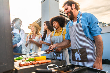 Friends grilling food and drinking beer on rooftop terrace